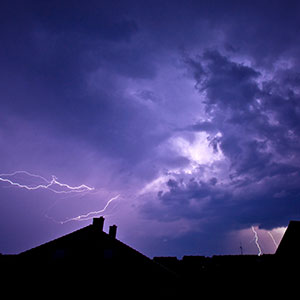 A dark, stormy sky with lightning over a residential neighborhood