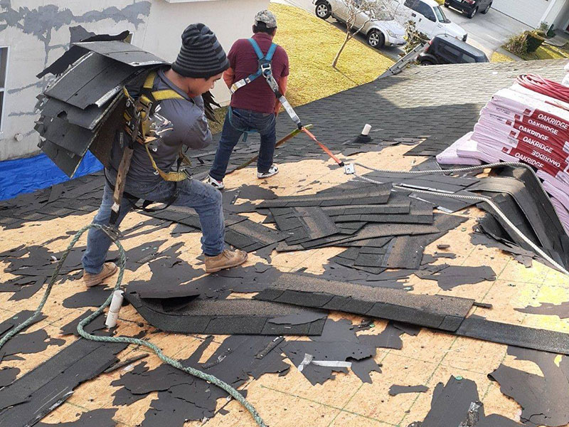 Arica Roofing & Construction LLC team members taking out the old shingles of a residential roof and getting it ready for new shingles